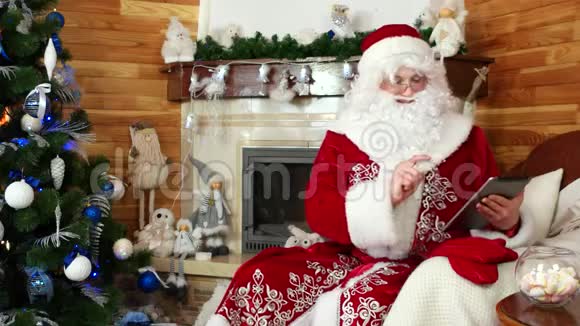 圣诞老人用小工具圣尼古拉斯坐在椅子上用电子设备新想法视频的预览图