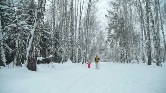 冬天森林里滑雪的女人和小女孩视频的预览图