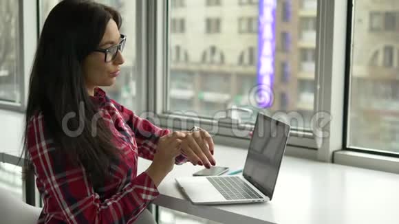 希普斯特混合种族妇女使用智能手表和笔记本电脑在咖啡馆工作视频的预览图