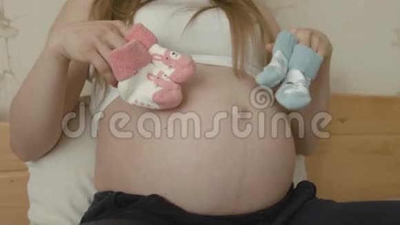 孕妇为新生儿穿着粉色和蓝色袜子视频的预览图