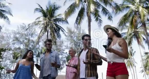 人群谈话交流利用手机智能手机走出棕榈树下快乐微笑混合种族男女视频的预览图