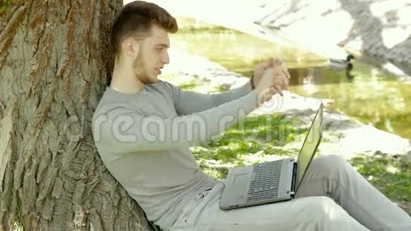 在树下的公园里学生弯曲脚趾在笔记本上做笔记视频的预览图
