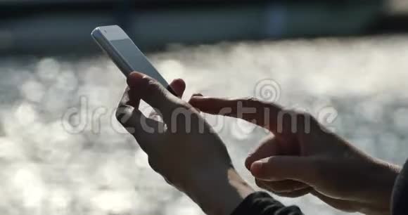 一个女孩在海边使用智能手机闪闪发光的水面视频的预览图