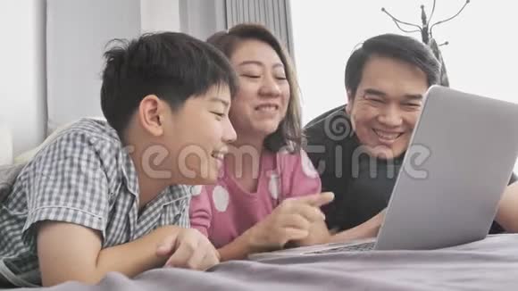 快乐的一家人爸爸妈妈儿子看着笔记本电脑玩得开心视频的预览图