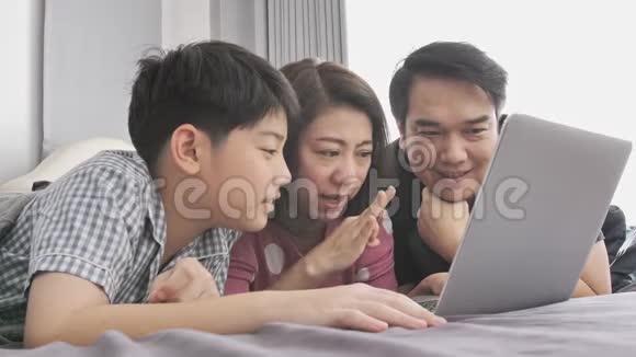 快乐的一家人爸爸妈妈儿子看着笔记本电脑玩得开心视频的预览图