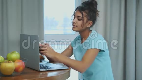 用一次性的咖啡杯和牛角面包裁剪女性手的快照桌上的笔记本电脑和配件视频的预览图