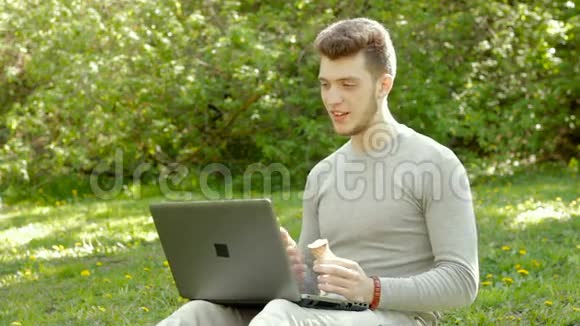 帅哥通过笔记本电脑在公园里聊天吃冰淇淋视频的预览图