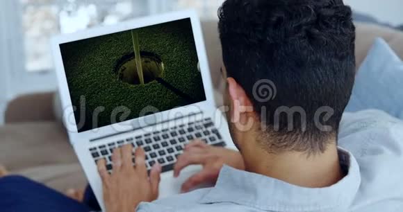 在客厅里看手提电脑高尔夫球的男人视频的预览图