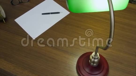 作家桌子上有书钟眼镜干净的纸和绿色的灯视频的预览图