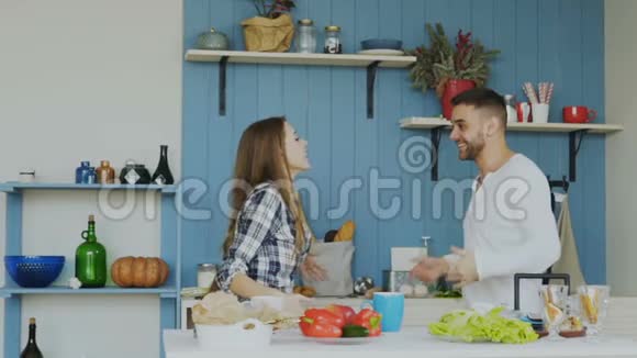 一对快乐而有魅力的年轻夫妇在爱中跳舞在家里的厨房里跳摇滚舞视频的预览图