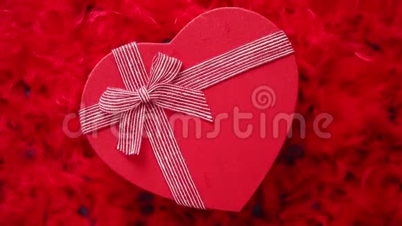 心形盒装礼物放在红色羽毛背景上视频的预览图