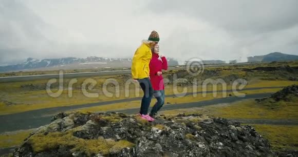 朋友们站在山顶上跳着幸福的舞蹈冰岛熔岩场的两个女人视频的预览图