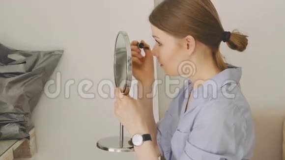 年轻的女人照镜子自己化妆眉毛视频的预览图
