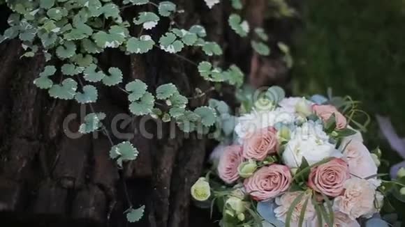 美丽的婚礼花束白色玫瑰和奶油康乃馨在一棵橡树附近的草地上视频的预览图