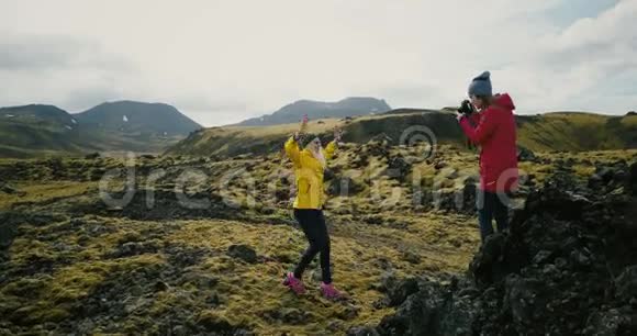 摄影师在山上为旅游妇女拍照在冰岛的熔岩场拍照片的女孩视频的预览图