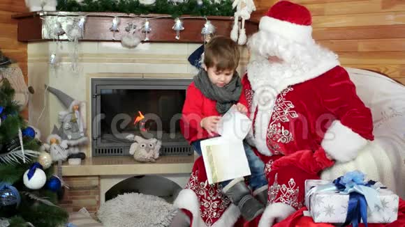 小男孩打开他的圣诞信孩子坐在桑塔斯大腿上孩子访问圣尼古拉斯住宅视频的预览图