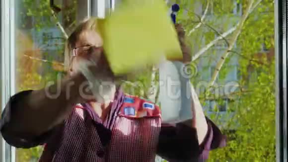 年长的女人带着微笑做作业洗窗户用喷雾剂清洗窗外春天视频的预览图
