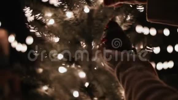女人在圣诞树上装饰着红色圣诞球背景是bokeh灯视频的预览图
