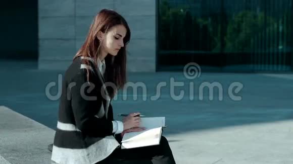 可爱的女人在户外的书里做笔记视频的预览图