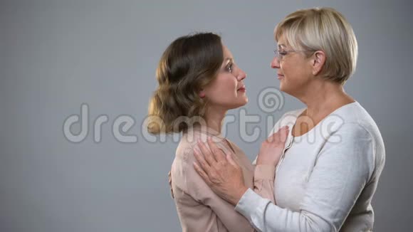 成熟女人在灰色背景下拥抱成年女儿母亲支持视频的预览图