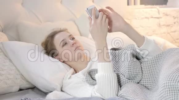 在床上使用智能手机的年轻女子视频的预览图