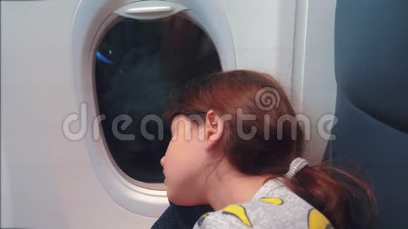 航空飞机概念坐在窗边的小女孩睡在飞机上夜间飞行生活方式视频的预览图