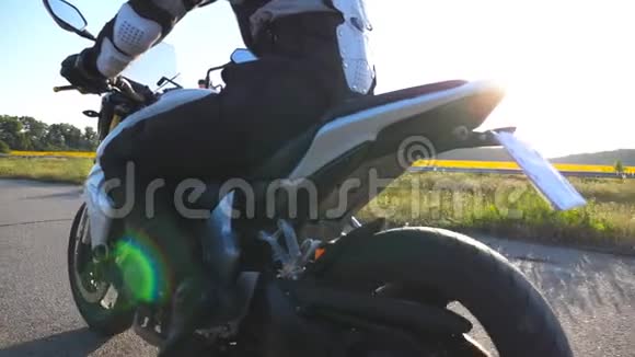 日落时骑摩托车的摩托车在乡村公路上行驶年轻人骑着摩托自行车慢动作后视频的预览图