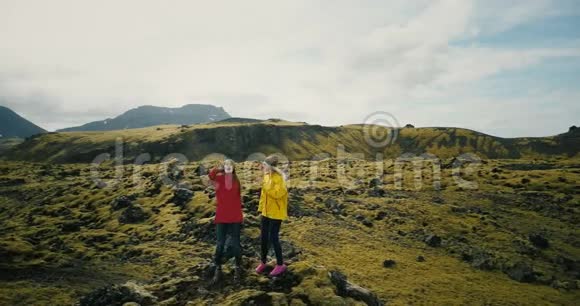 冰岛熔岩场上的两个女人的空中景色举手快乐的游客送空气亲吻给复印机视频的预览图