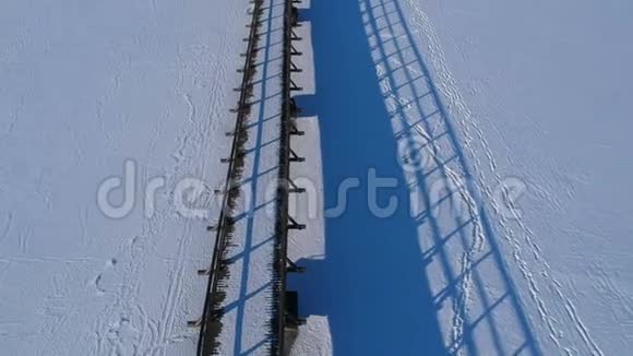 在雪地上有蓝色阴影的老木桥空中视频的预览图