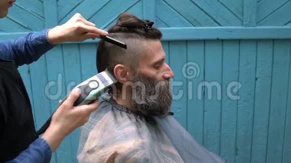 女理发师在露天理发店用电动剃须刀理发视频的预览图