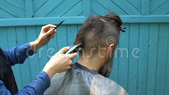 女理发师在露天理发店用电动剃须刀和梳子理发视频的预览图