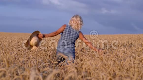 在一个阳光明媚的日子里一个女人穿着一件白色的衣服戴着一顶草帽在一片麦田里行走这是一个自然概念视频的预览图