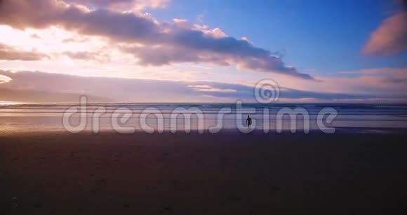 日落时分冲浪者朝大海走去视频的预览图