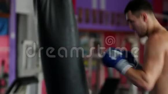 一名职业拳击手正在赤胸露体地对拳击袋进行打击垂直摄像机视频的预览图