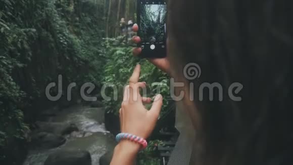 在一条小河的丛林中的手在用智能手机拍一张照片视频的预览图