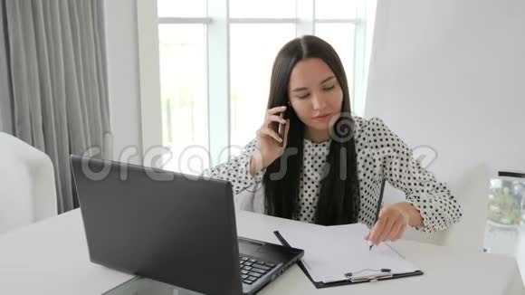 漂亮的秘书在白色办公室打电话女经理在桌子上的笔记本上打印文本员工说话视频的预览图