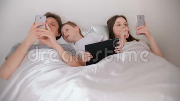 家人正在使用手机和平板电脑躺在床上视频的预览图
