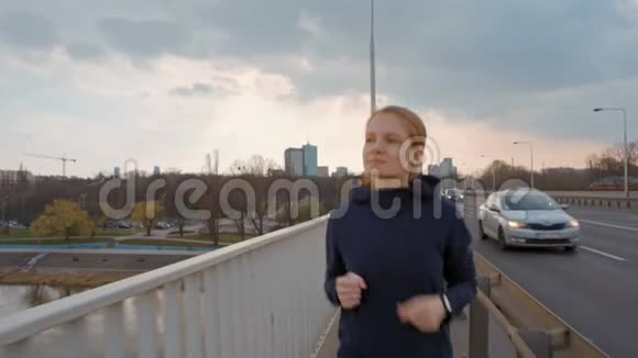 年轻女士在城市的桥上奔跑的慢动作慢跑前景视频的预览图