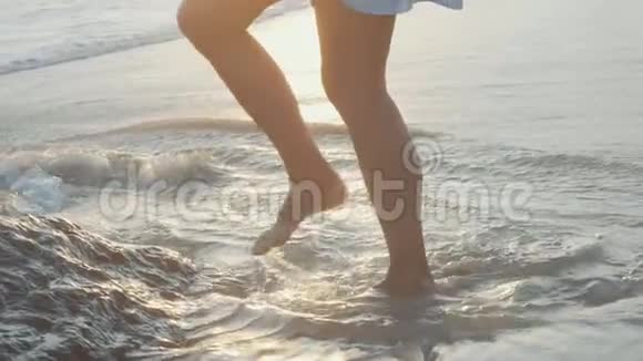 赤裸的雌性脚在岩石海滩上行走双腿穿过海岸上的石头视频的预览图