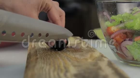 女人在厨房桌子上切橄榄做披萨在木切割板上切菜视频的预览图