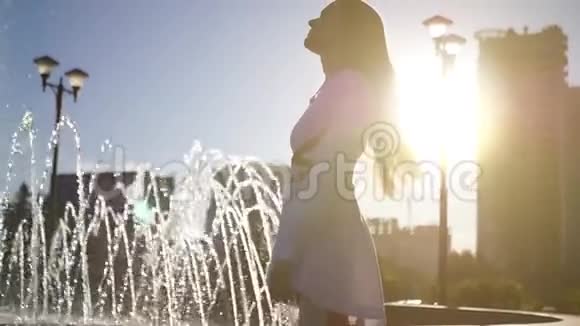 一个美丽苗条的女孩在喷泉旁旋转充满了幸福和自由高清1920x1080慢动作视频的预览图