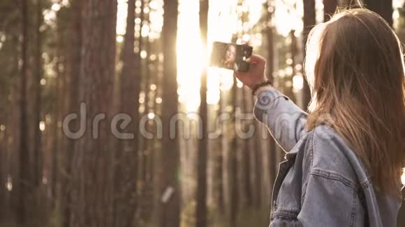 在森林智能手机拍照的年轻女孩视频的预览图