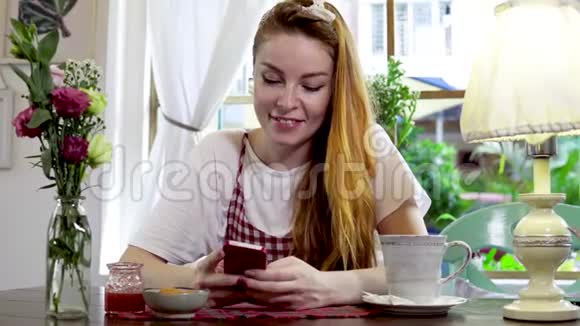 女人一边喝茶一边用手机写信息视频的预览图