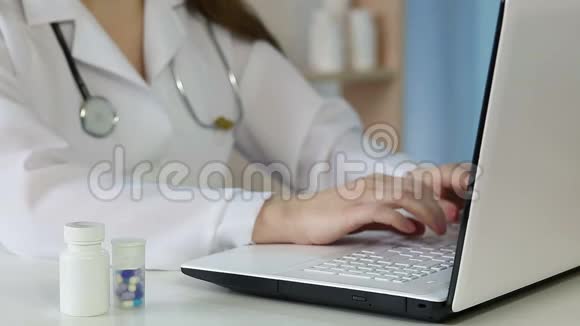 穿着白色外套的女性医学博士使用笔记本电脑为病人输入在线处方视频的预览图
