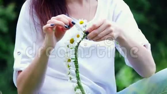 夏天肖像在一片洋甘菊草坪的中间在一片森林里一个年轻的女人一个深色头发的女人着一个甘菊花圈视频的预览图