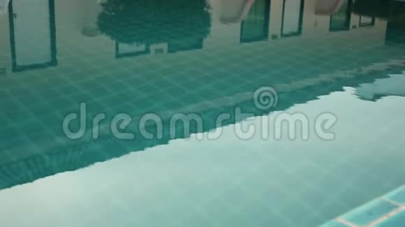 戴太阳镜的年轻女子在游泳池里放松和慢慢游泳视频的预览图