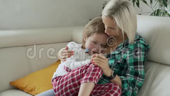 母亲在后台测量生病孩子的体温病儿高烧躺在家里的沙发上视频的预览图