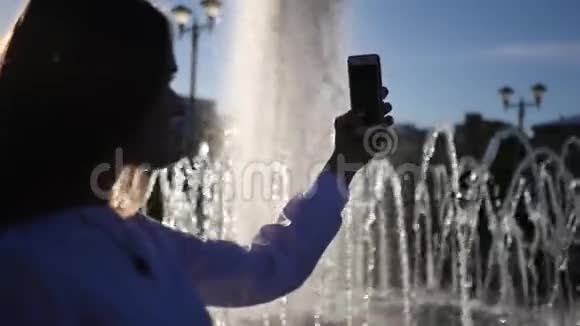 一个留着长发的漂亮女孩在喷泉前拍了一张照片背景模糊高清1920x1080慢慢慢慢视频的预览图