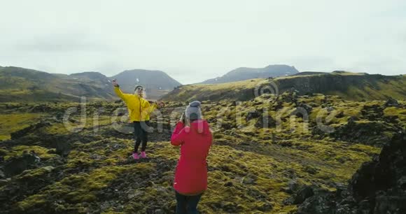 直升机在山上拍摄有照片的游客两个女人在冰岛的熔岩场拍照视频的预览图