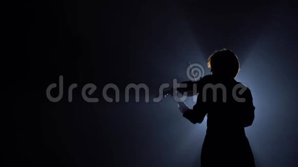 女孩们站在后面在黑暗的房间里演奏小提琴黑烟背景背面视频的预览图